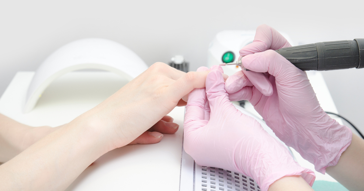 Profesional de manicura usando guantes rosas de nitrilo para realizar un tratamiento, guantes de examen para estética