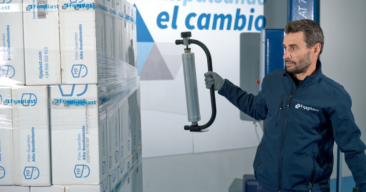 operario aplicando film estirable manual a un palet con dispensador. Qué es paletización